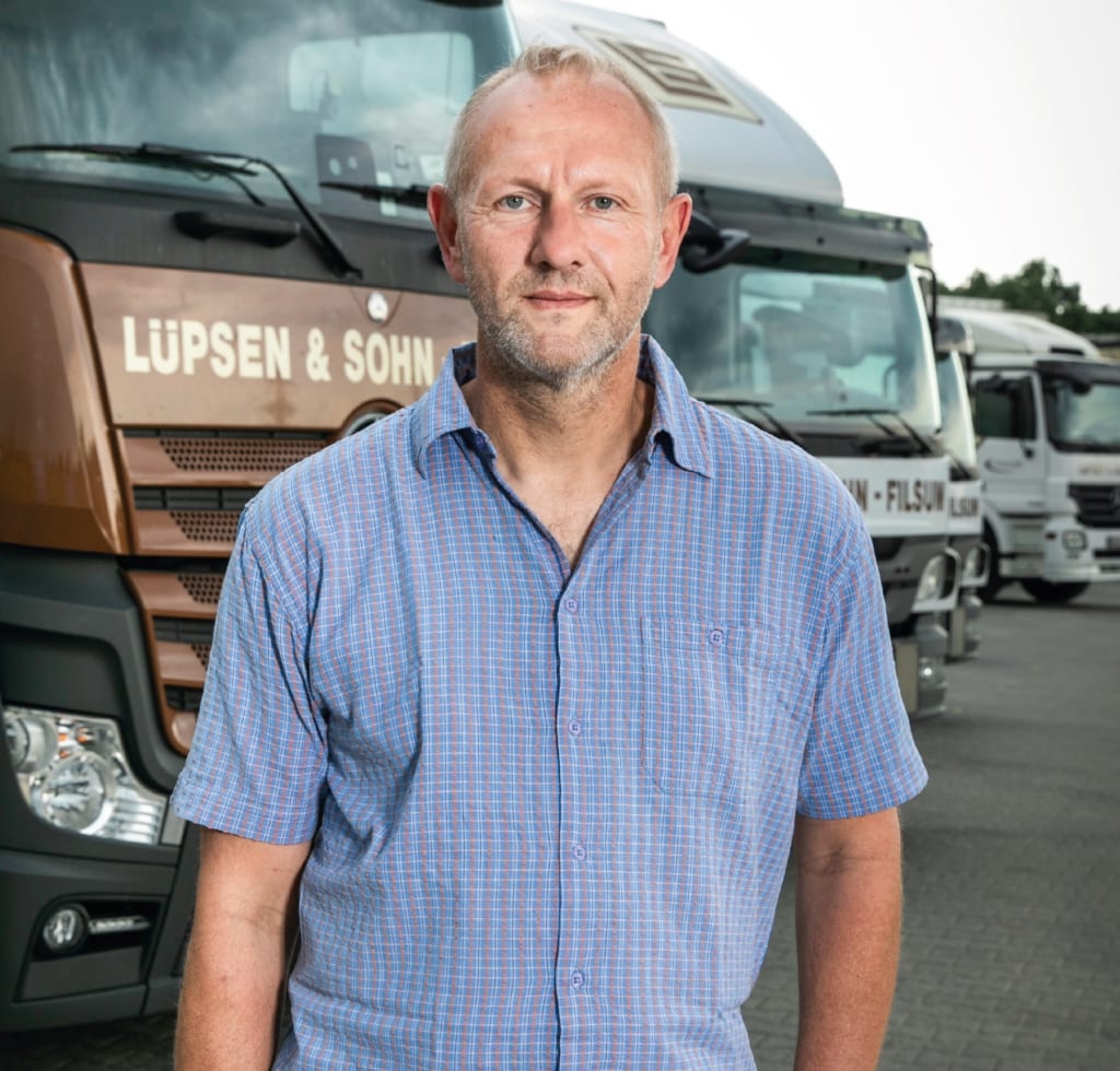 Dirk Lüpsen met op de achtergrond een rij vrachtwagens