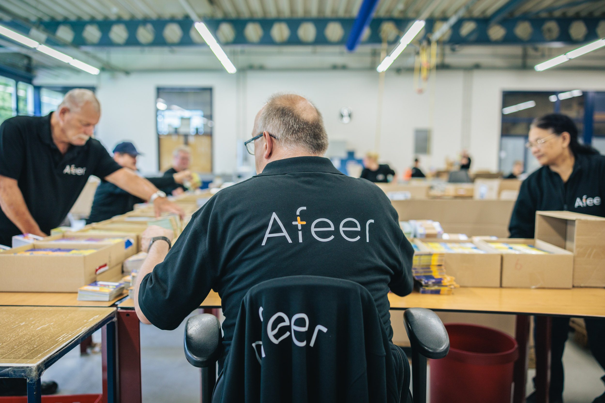 Een medewerkersvan Afeer, op de rug gezien, is boekjes aan het inpakken