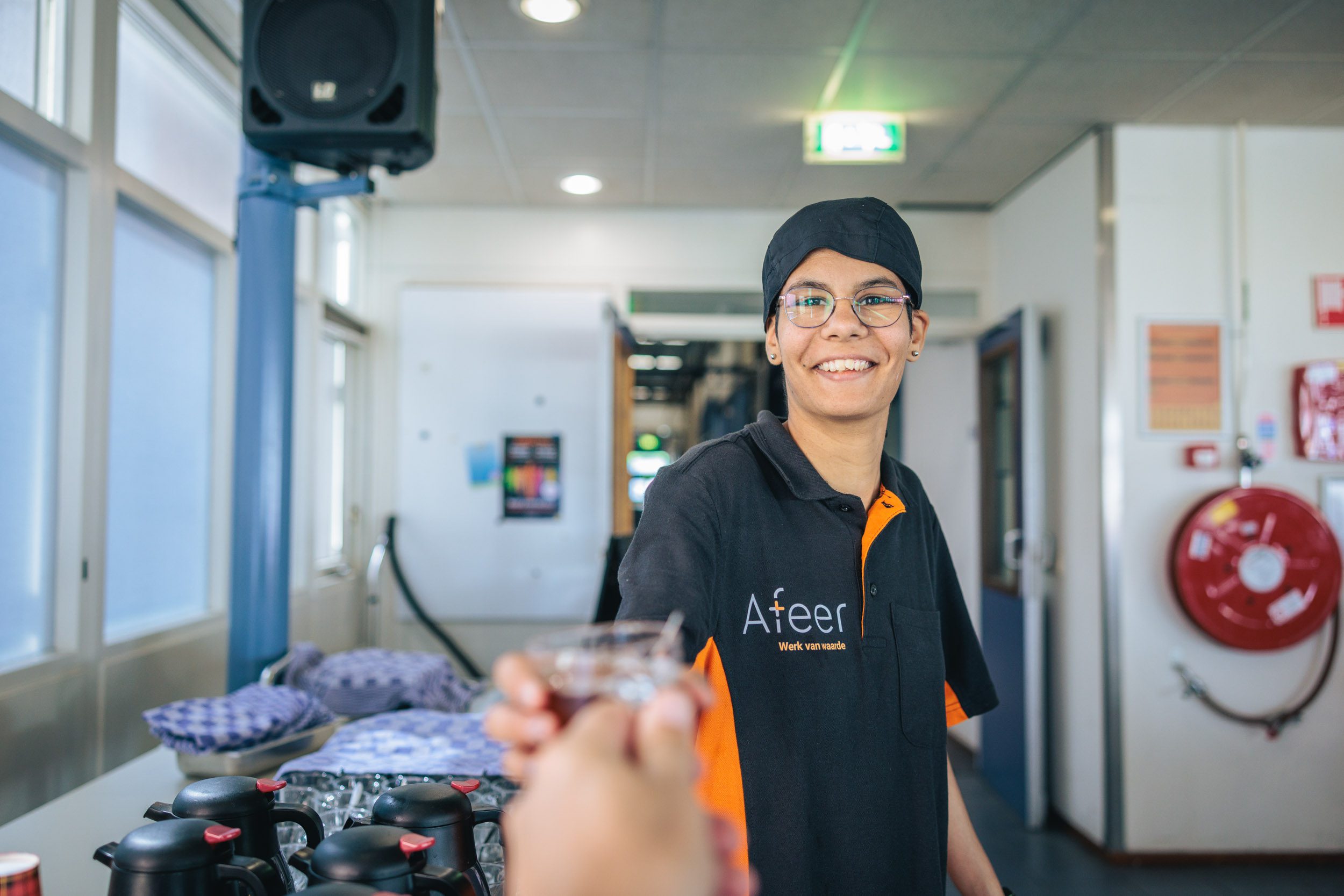 Een medewerkster van het bedrijfsrestaurant van Afeer kijkt lachend naar de camera