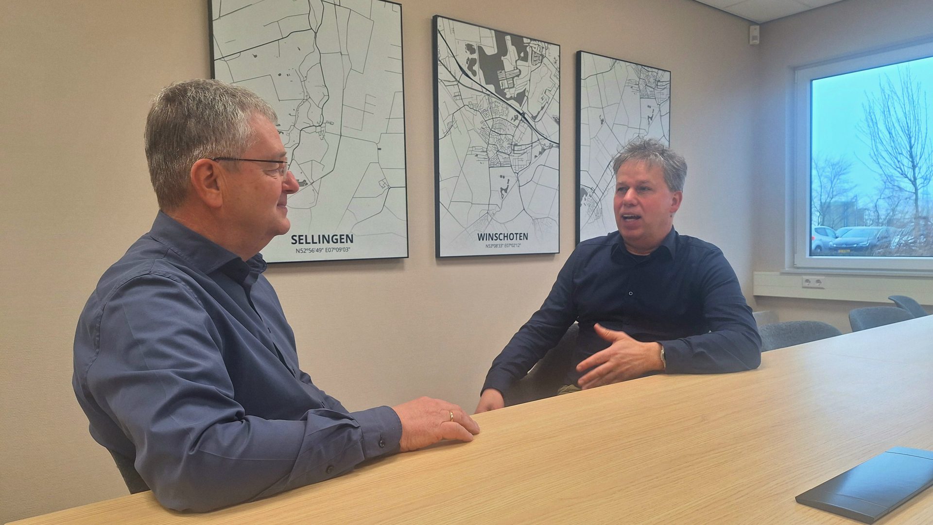 Bé Wever en Jurrie Modderman zitten aan een vergadertafel te praten